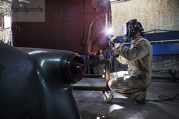 Mechaniker  der in einer Autowerkstatt an einem Fahrzeugteil arbeitet