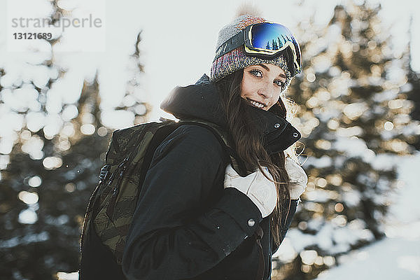 Porträt einer selbstbewussten jungen Frau mit Rucksack  die im Winter eine Skibrille trägt