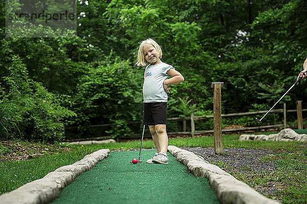 Porträt eines lächelnden Mädchens  das den Putter hält  während es auf dem Golfplatz steht