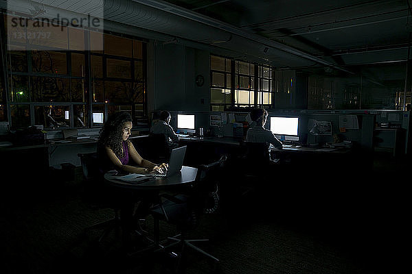 Geschäftsleute  die nachts in einem dunklen Büro arbeiten