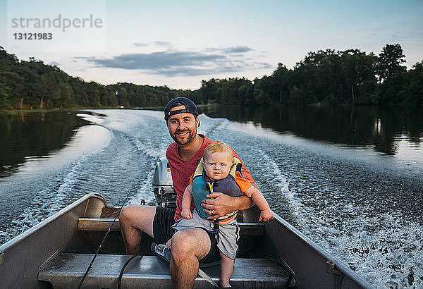 Porträt eines Vaters mit Sohn im Motorboot auf dem See sitzend