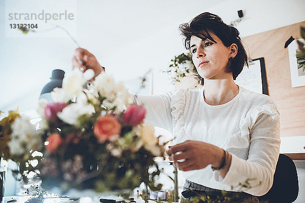 Zuversichtlicher Florist beim Arrangieren von Blumen im Geschäft