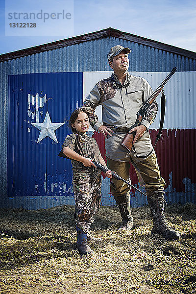 Familie steht auf Feld mit Gewehr gegen Texas-Flagge