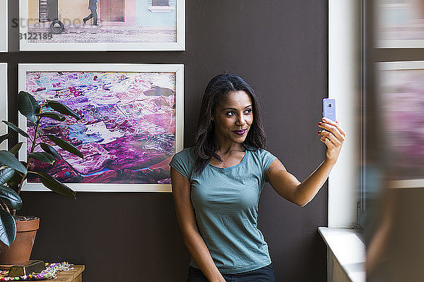 Frau nimmt Selbstliebe  während sie sich zu Hause an Bilderrahmen an der Wand stellt