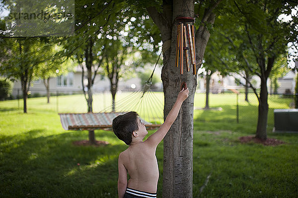 Junge ohne Hemd spielt mit Windspiel  während er im Hinterhof steht