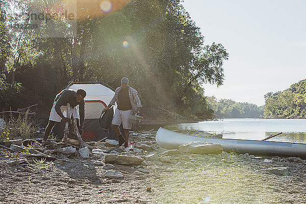 Männliche Freunde stehen auf dem Campingplatz am See