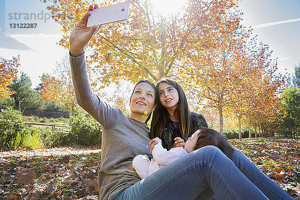 Lächelnde Mutter mit Töchtern im Herbst im Park