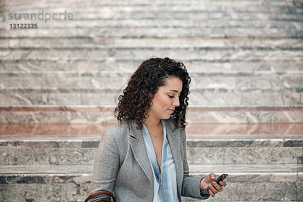 Geschäftsfrau benutzt Smartphone auf Treppen im Freien