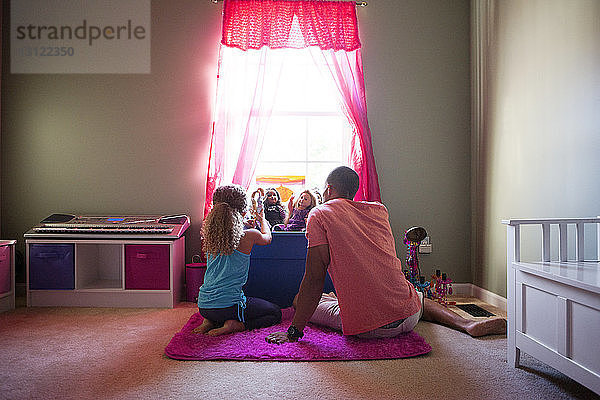 Rückansicht von Vater und Tochter beim Spielen mit Puppen im heimischen Schlafzimmer