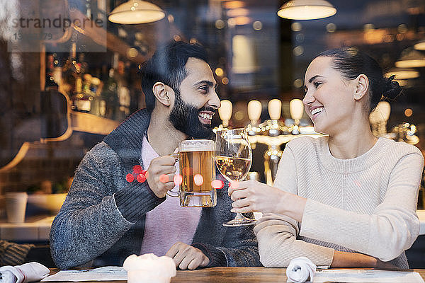 Glückliches Paar trinkt durch Restaurantfenster gesehen