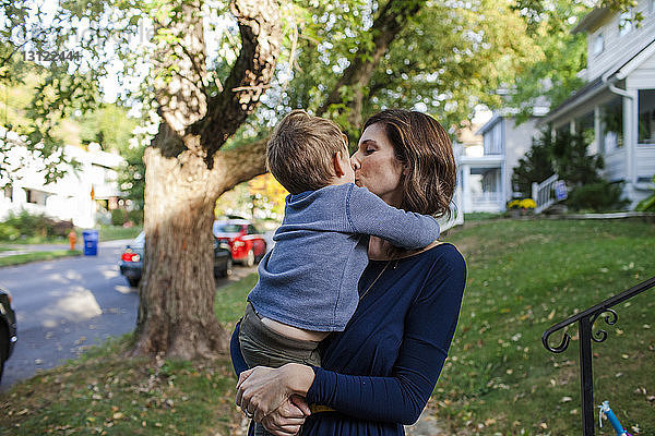 Mutter küsst Sohn  während sie an Bäumen steht