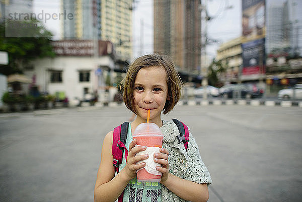 Porträt eines Mädchens  das im Stehen in der Stadt trinkt