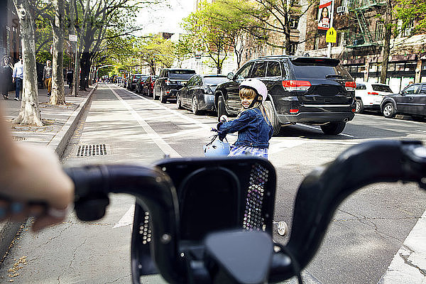 Mädchen sieht Mutter beim Fahrradfahren auf der Straße an