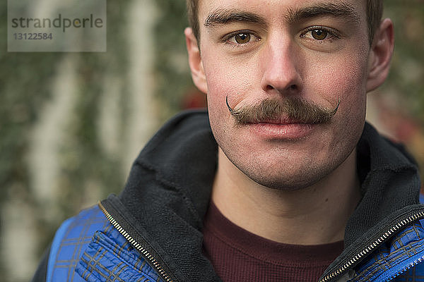 Nahaufnahme eines selbstbewussten Mannes mit Schnurrbart im Hinterhof
