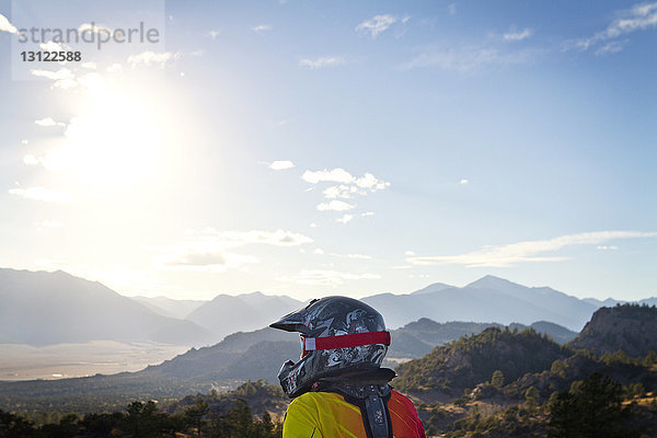 Schmutziger Radfahrer  der am sonnigen Tag Berge gegen den Himmel schaut