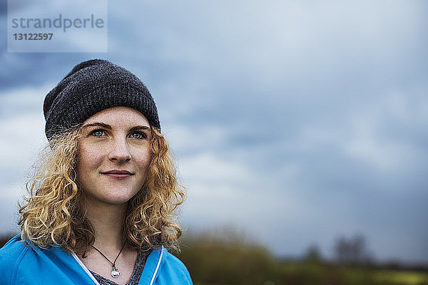 Nachdenkliche Sportlerin schaut weg gegen bewölkten Himmel