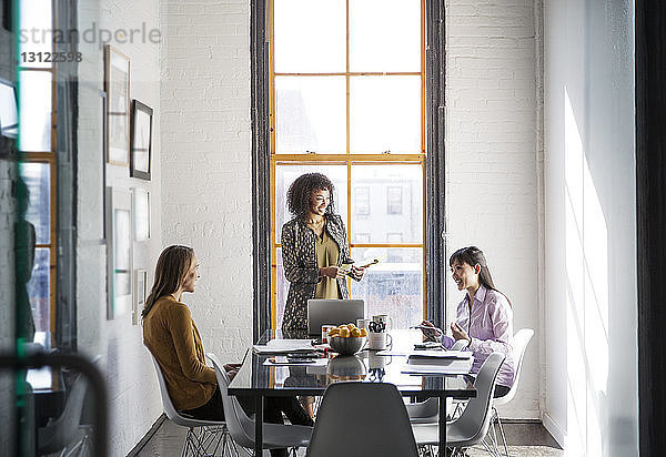 Geschäftsfrauen diskutieren am Tisch gegen Fenster im Kreativbüro