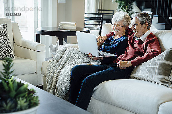 Glückliches älteres Ehepaar bei Videokonferenzen über Laptop-Computer im Wohnzimmer