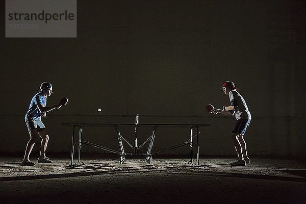 Männliche Freunde spielen Tischtennis gegen Gebäude