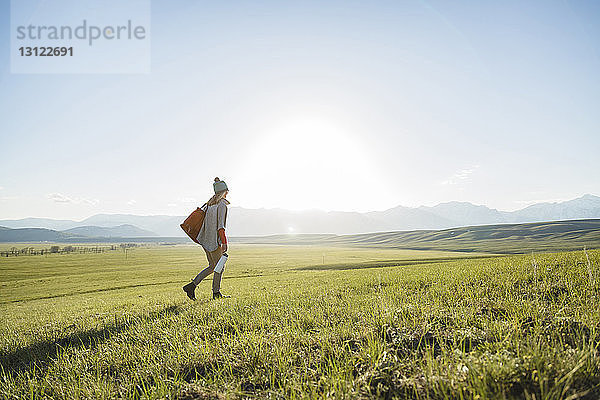 Rückansicht einer Wanderin auf einem Grasfeld bei klarem Himmel