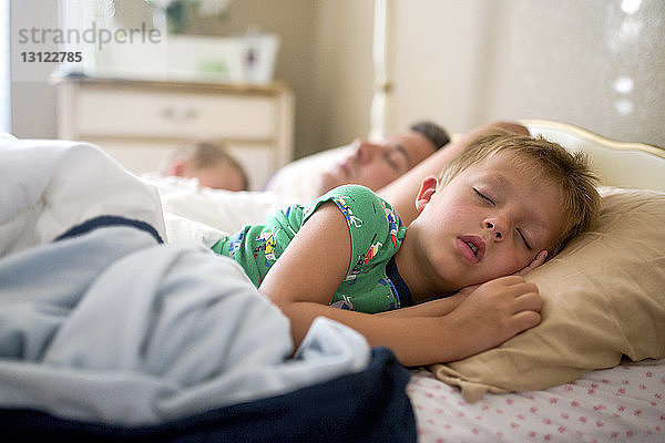Vater und Söhne schlafen zu Hause im Bett