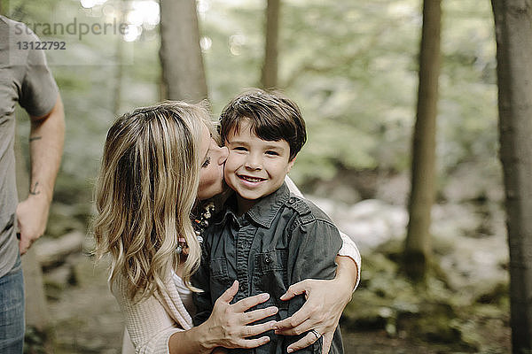 Mutter küsst Sohn  während sie mit Ehemann im Wald steht