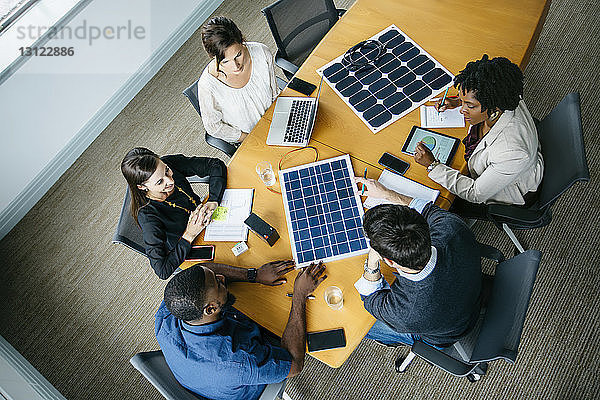Draufsicht auf Geschäftsleute  die während des Treffens über Solarpanel-Modelle diskutieren