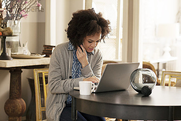 Frau benutzt Laptop-Computer  während sie am Tisch sitzt