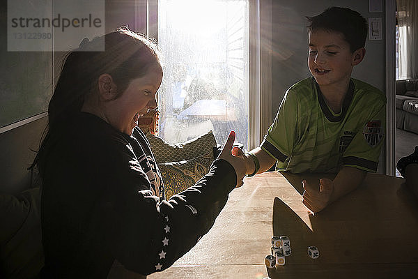 Glückliche Geschwister Daumenkampf zu Hause auf dem Tisch