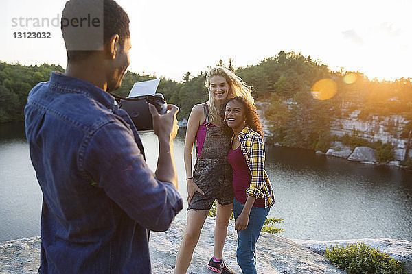 Junger Mann fotografiert Freunde im Urlaub mit Sofortbildkamera