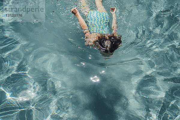 Hochwinkelansicht eines Mädchens  das an einem sonnigen Tag im Pool schwimmt
