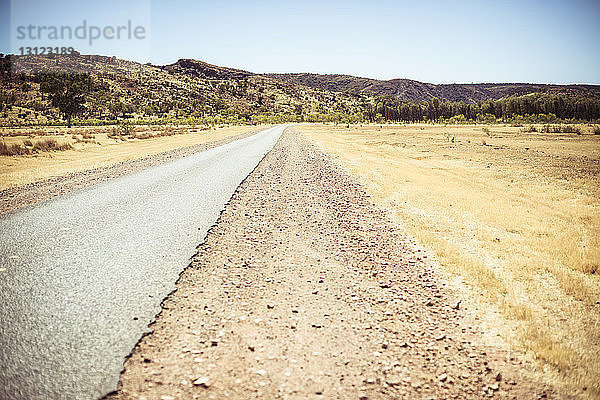 Straße inmitten der Landschaft gegen klaren Himmel in der Wüste bei Sonnenschein