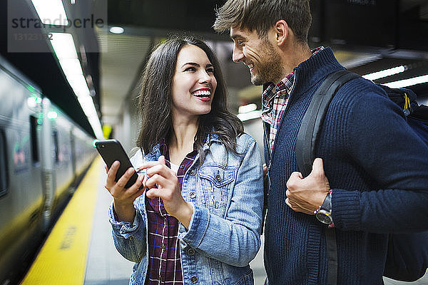 Paar  das sich anschaut und lächelt  während es in der U-Bahn-Station steht