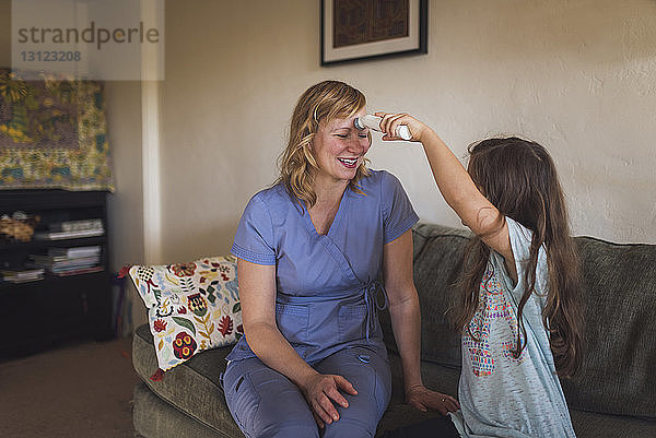 Mädchen gibt einer Ärztin eine Kopfmassage  während sie zu Hause auf dem Sofa sitzt
