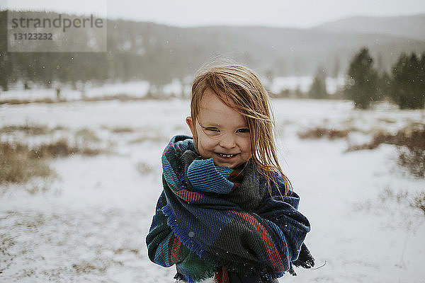 Porträt eines glücklichen Mädchens  das im Winter in eine Decke gehüllt ist