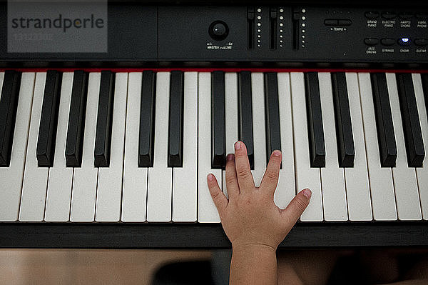 Abgehackte Hand eines Jungen  der zu Hause Klavier spielt