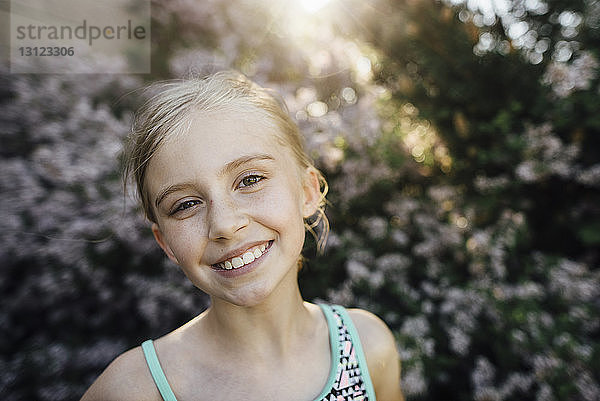 Porträt eines lächelnden Mädchens  das im Hinterhof vor Pflanzen steht