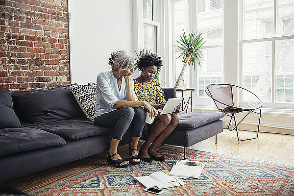 Geschäftsfrauen mit Tablet-Computer auf dem Sofa im Kreativbüro