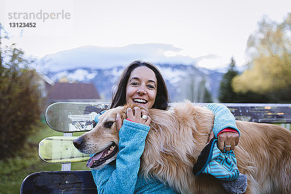 Bildnis einer fröhlichen Frau mit Hund auf einer Parkbank sitzend