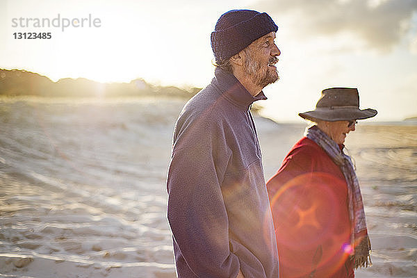 Glückliches älteres Ehepaar beim Strandspaziergang an einem sonnigen Tag