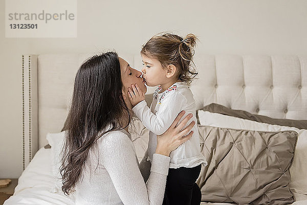 Liebende Mutter und Tochter küssen sich zu Hause auf den Mund