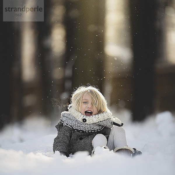 Porträt eines fröhlichen Mädchens  das im Schnee im Park spielt