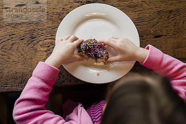 Draufsicht eines Mädchens mit Donut am Tisch
