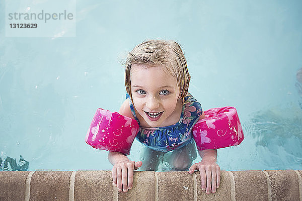 Porträt eines glücklichen Mädchens mit Schwimmflügeln im Pool