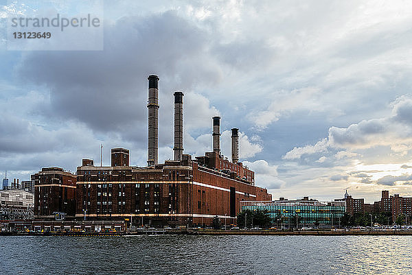 Fabrik am East River in der Stadt gegen bewölkten Himmel