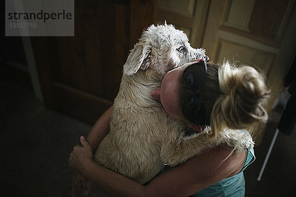 Hochwinkelansicht einer Frau  die einen Hund zu Hause umarmt