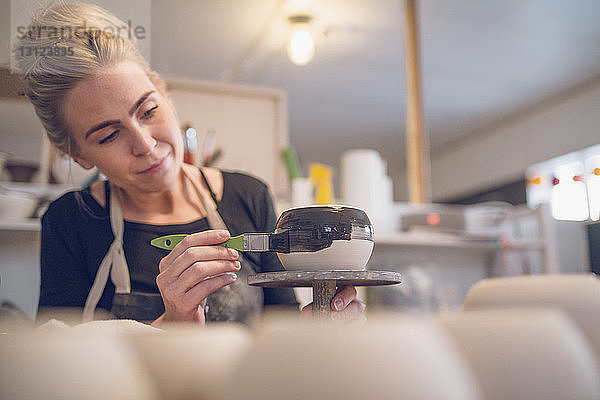 Niederwinkelansicht einer Frau  die in einem Workshop Keramik bemalt