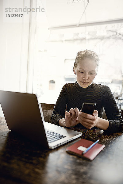 Junge Frau benutzt Smartphone im Café