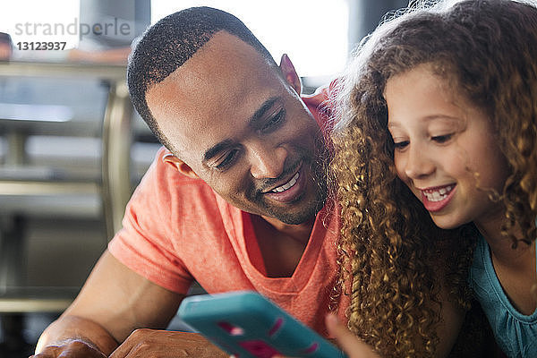 Nahaufnahme von Vater und Tochter beim Spielen eines Videospiels  während sie zu Hause liegen