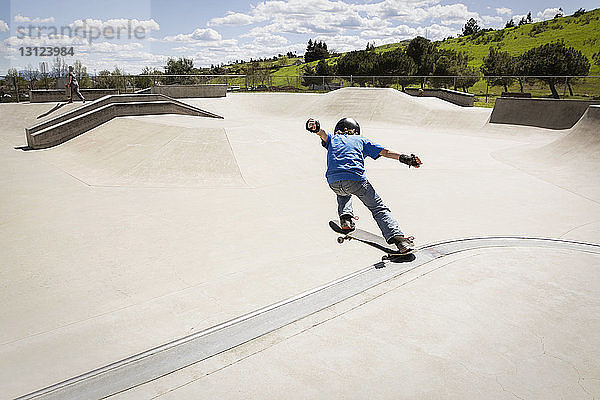 Schrägansicht eines Jungen  der auf einer Skateboard-Rampe einen Stunt macht